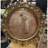 A 19th Century circular carved giltwood frame, enclosing a sepia print of a young lady gathering