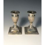 A pair of Victorian Adams style filled silver low candlesticks with fluted vase shaped bodies and