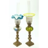 Two glass and brass oil lamps, surmounted on a pair of Victorian brass candlesticks. (Dimensions: