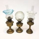 A group of three brass oil lamps, shades and chimneys, late 19th century and later. (Dimensions: The