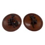A pair of early 20th century bronze cherubs mounted on mahogany circular plaques. (Dimensions: