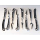 A set of six small two tined silver forks with filled silver acanthus capped pistol grip handles