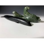 Three Inuit soapstone carvings of seals, height 11cm diminishing, and a slate carving of a whale,