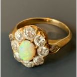 A gold ring with small oval opal surrounded by old cut diamonds and with diamond shoulders.