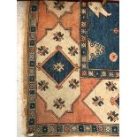 A Milas Turkish carpet, the madder field with polychrome medallions, indigo spandrels, within a