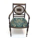 A mahogany open armchair, 19th century, the oval rattan splat with a central carved wood panel above