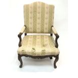 A 19th century upholstered carved walnut armchair, with acanthus leaf carved cabriole legs. (