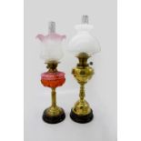 A late 19th/early 20th century brass oil lamp with cranberry reservoir and etched glass shade, on