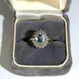 An 18ct gold ring set an aquamarine surrounded by small diamonds, those at the shoulders are