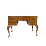 A George III style walnut writing desk, the triple red leather inset top above an arrangement of