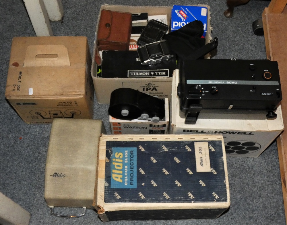 A collection of photographic photography equipment including projector, folding cameras, box