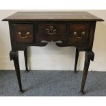 A Georgian oak lowboy fitted with three drawers, cabriole legs with shell caps