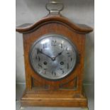 An oak cased mantle clock on raised brass feet with brass handle to top