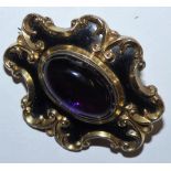A Victorian gold, black enamel brooch set with a cabochon amethyst