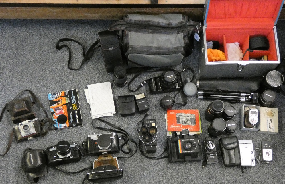 A collection of cameras together with a camera bag with Olympus camera and various lenses together