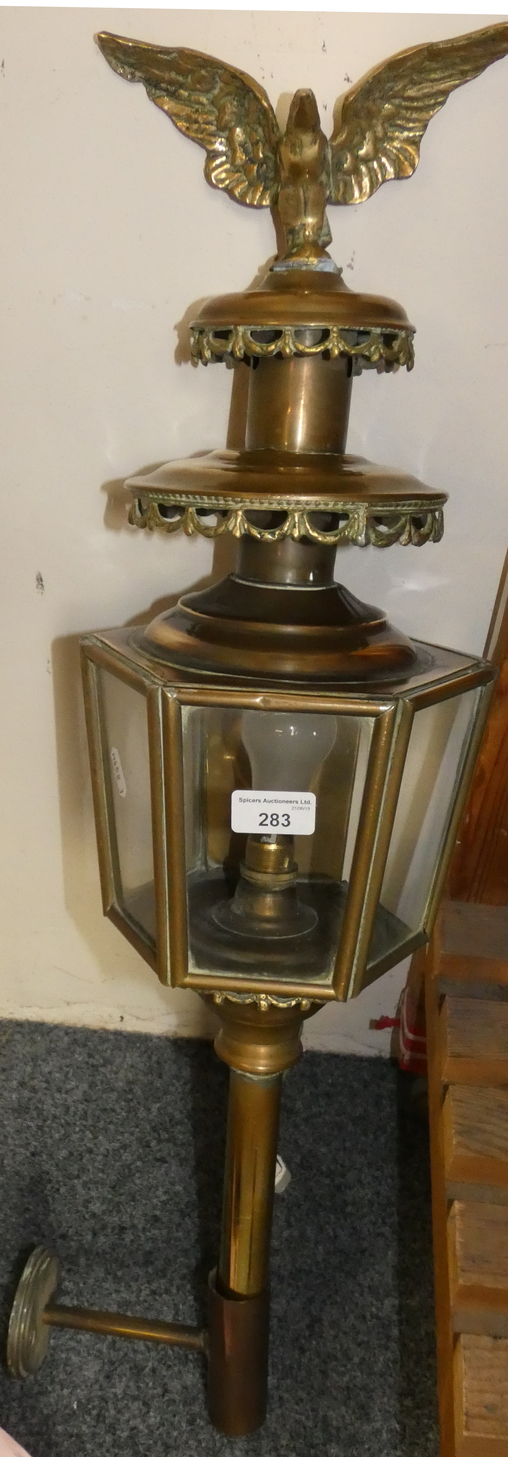 A brass carriage style lamp with brass eagle figure to top