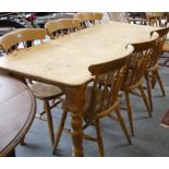 A stripped pine kitchen table, 183 cm x 83 cm together with a set of seven spindle back chairs,