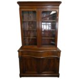 A Victorian mahogany bookcase cabinet, the upper section with glazed doors over a shaped base with