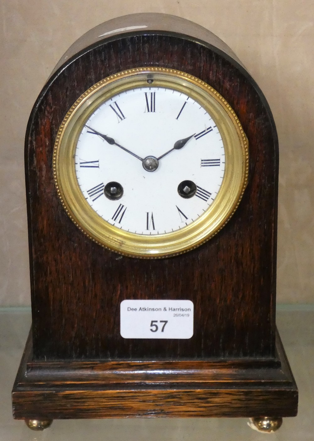 A domed oak cased mantle clock on brass ball feet