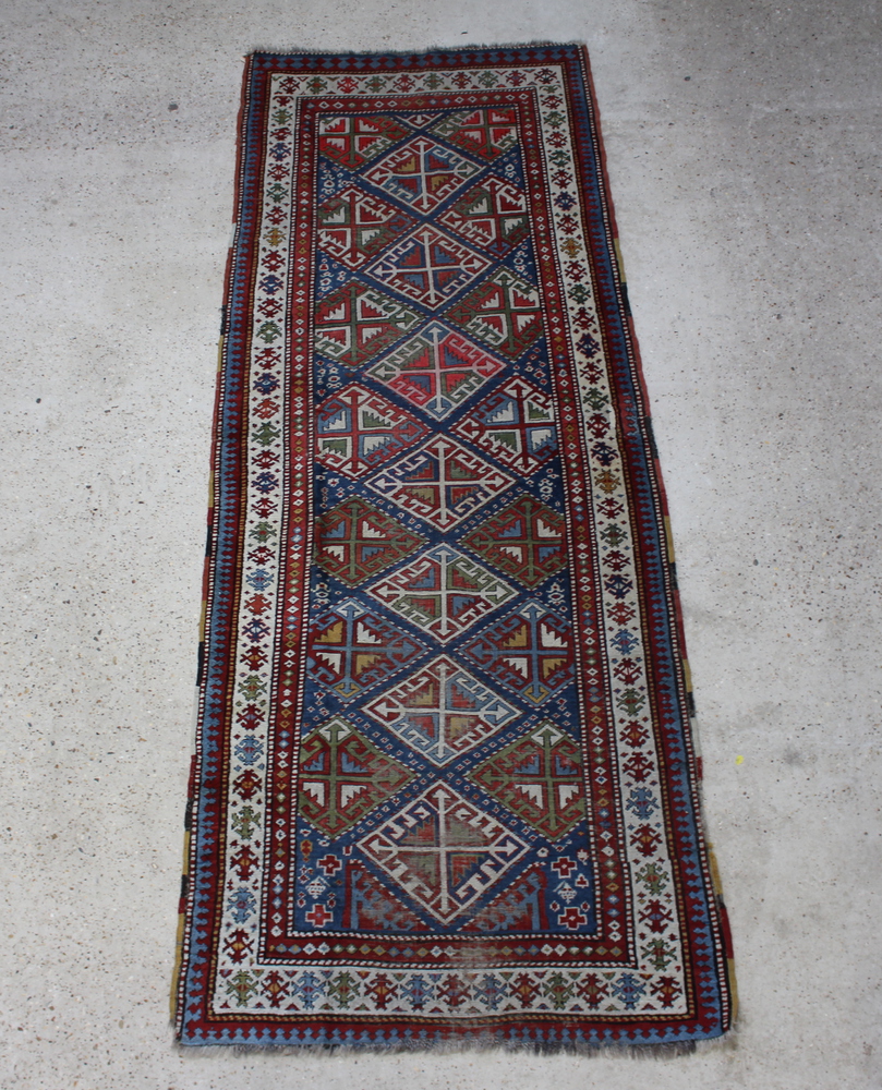 An Antique Caucasian runner with 7 diamonds to the centre within multi row borders 298cm x 111cm