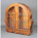 A 1930's Art Deco arched walnut display cabinet fitted adjustable shelves enclosed by astragal