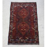 A brown and black ground Belouche rug with 2 stylised diamonds to the centre within a multi row