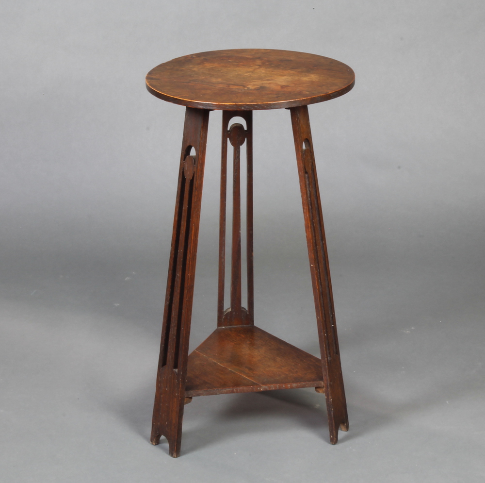 In the manner of Voisy, a circular Art Nouveau oak 2 tier occasional table/plant stand raised on 3