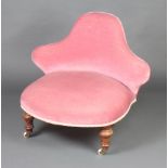 A Victorian nursing chair with shaped back, upholstered in rose pink material raised on turned