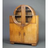 A 1930's Art Deco circular oak display cabinet on cabinet, the upper section fitted shelves enclosed