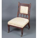 A late Victorian carved walnut nursing chair with upholstered seat and back, raised on turned