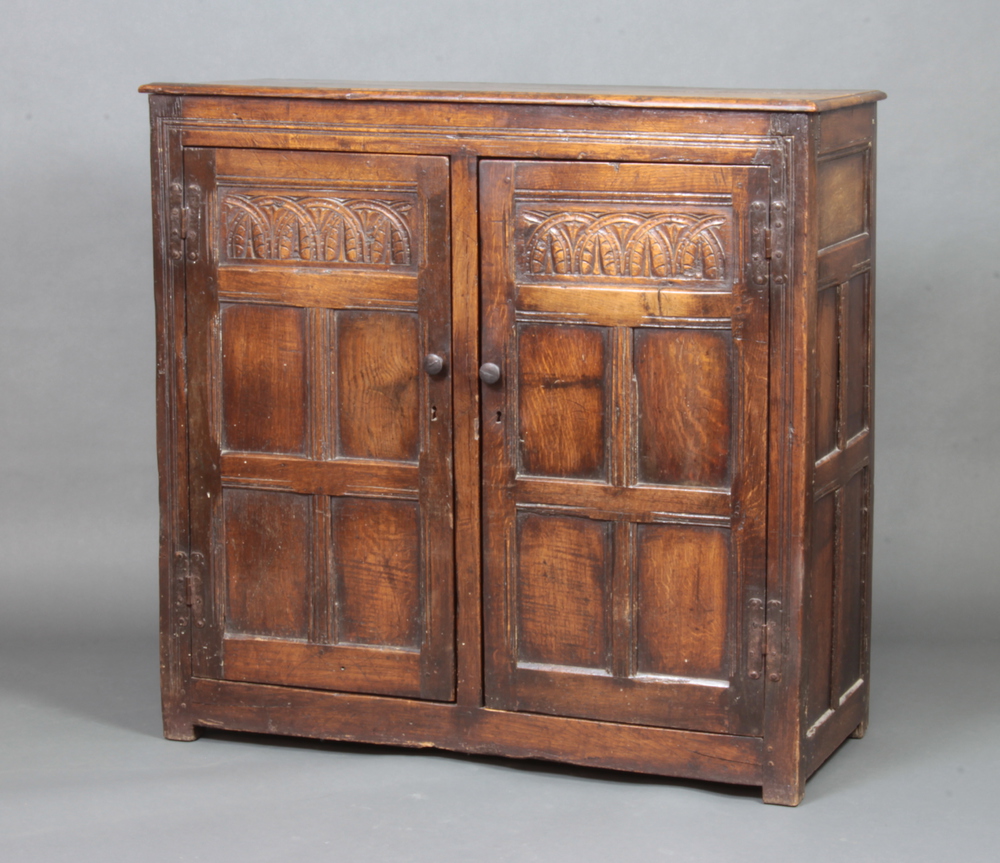 A 19th Century, 17th Century style carved oak cupboard enclosed by panelled doors, the top formed of