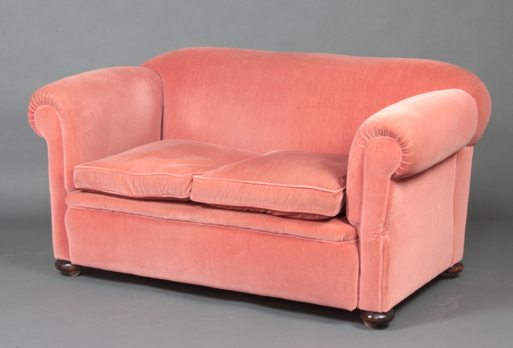 A Victorian drop arm Chesterfield upholstered in rose pink material, raised on bun feet 75cm h x