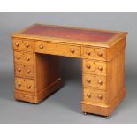 A Victorian light oak kneehole pedestal desk with inset writing surface above 1 long and 8 short