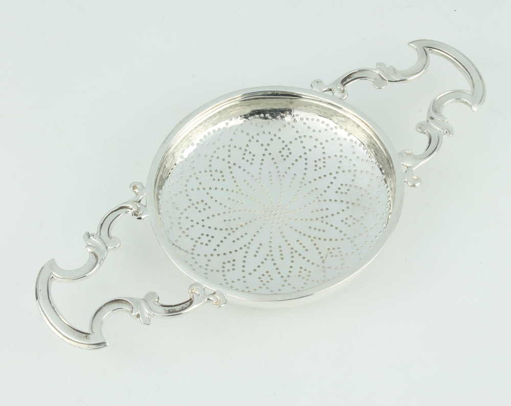 A Georgian design strainer with pierced geometric decoration and scroll handles, makers mark IWTB