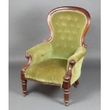A Victorian mahogany show frame armchair upholstered in green buttoned material, raised on turned