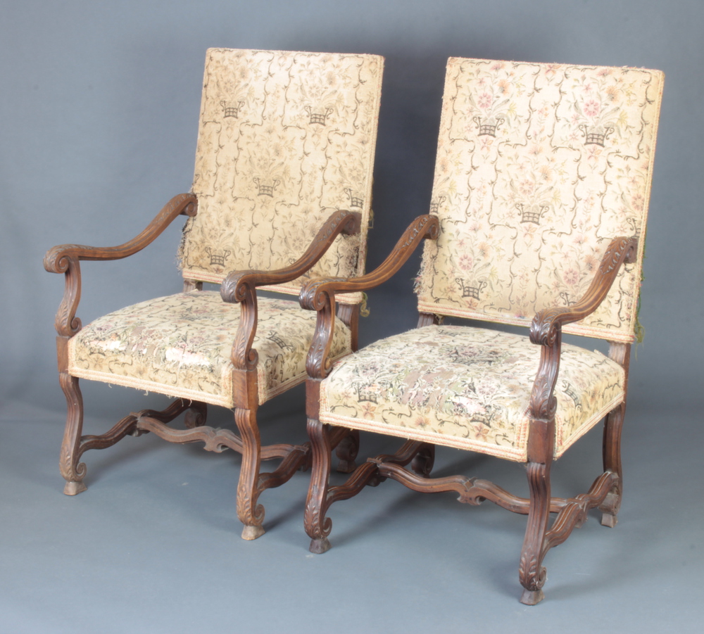 A pair of Italian style carved walnut open arm chairs, the seats and backs upholstered in