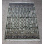 A green ground Bokhara style Belgian cotton rug with numerous octagons to the centre within a