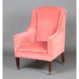An Edwardian winged armchair upholstered in rose pink velvet, raised on square tapered supports