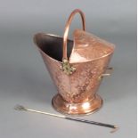 An Edwardian embossed copper and brass helmet shaped coal scuttle raised on a circular spreading