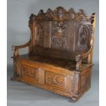 A 19th Century heavily carved oak settle the shaped raised back carved armorial decoration and