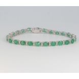 An 18ct white gold emerald and diamond line bracelet, the emeralds approx. 8.31ct, the diamonds 0.