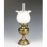 A brassed oil lamp with opaque glass shade and chimney