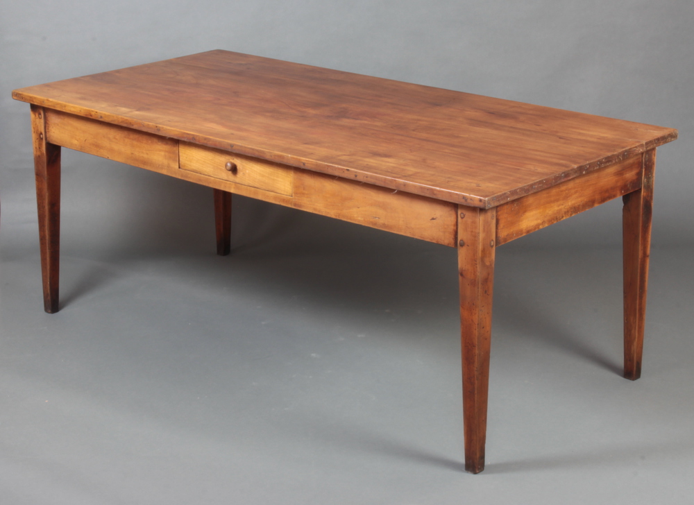 A 19th Century French cherry wood dining table, the top of plank construction, fitted a frieze