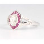 An 18ct white gold ruby and diamond ring, the centre oval cut diamond approx. 0.58ct surrounded by