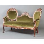 A Victorian carved mahogany show frame double spoon back settee upholstered in green material raised