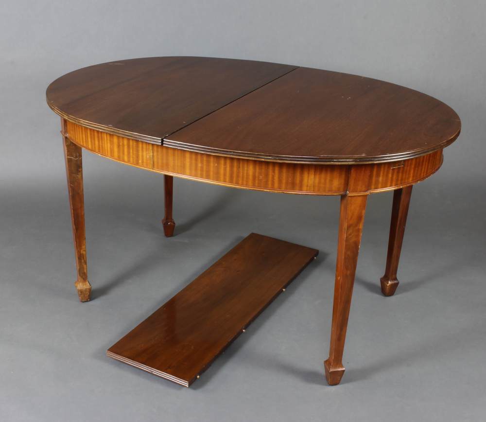 An Edwardian walnut oval extending dining table raised on square tapered supports, spade feet 75cm h