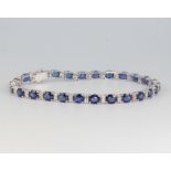 An 18ct white gold sapphire and diamond line bracelet, the sapphires approx. 11.22ct, the diamonds