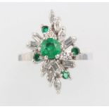 An 18ct white gold emerald and diamond floral ring set with 5 brilliant cut emeralds and baguette