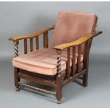 A 1930's oak reclining armchair with spiral turned decoration, the seat and back upholstered in