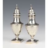 A pair of Georgian silver vase shaped peppers with chased armorial on square bases, 15.5cm, 190